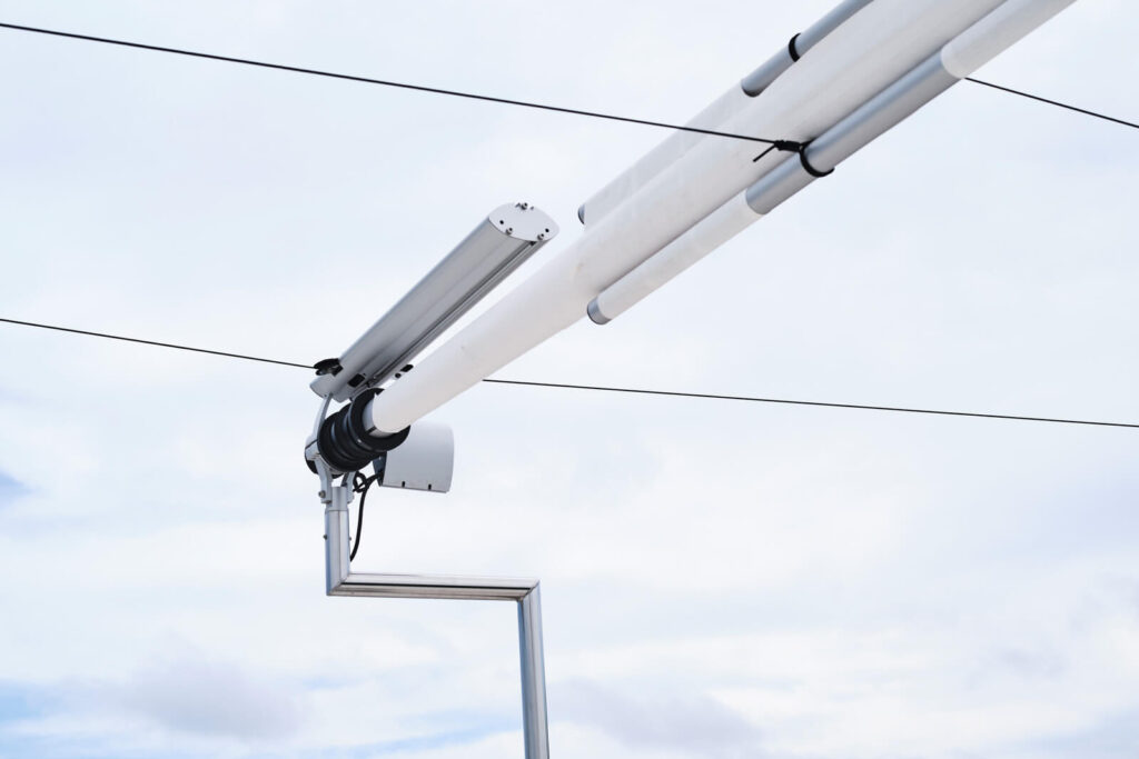 The patented soft-tension cable network distributes wind load energy across the sail geometry — enabling 80 m² retractable shade without oversized motor hardware or heavy structural elements.
