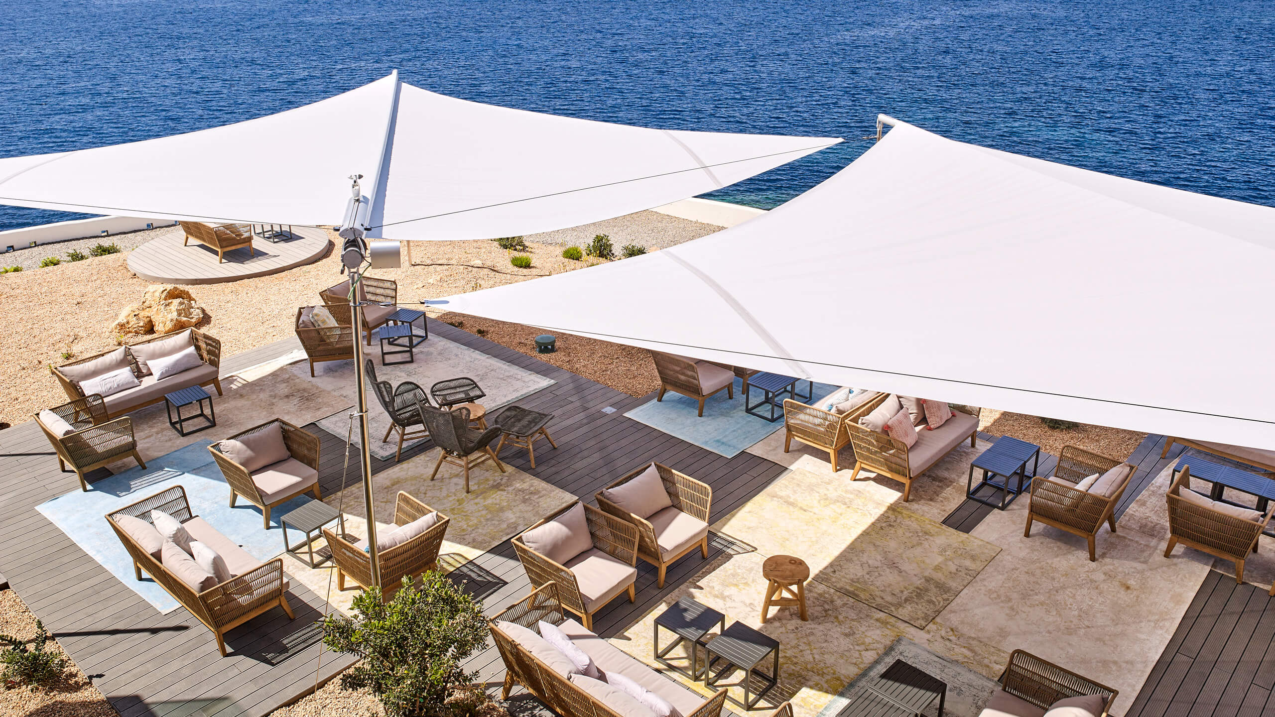Wind-resistant Sun Sail deployed over Balearic hotel or restaurant terrace — commercial specification, automatic wind retraction, large-span coverage across all four islands