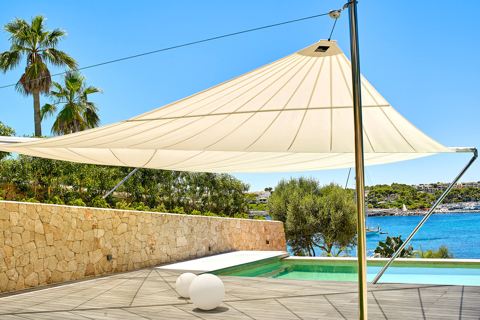 Completed SunSquare installation at Ibiza luxury pool terrace, large-span coverage with sea view in background