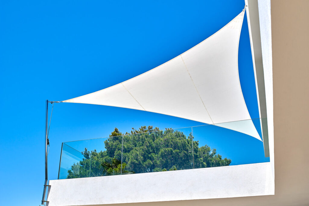 SunSquare automatic sun sail deployed over large whitewashed Ibiza villa terrace, sea view preserved